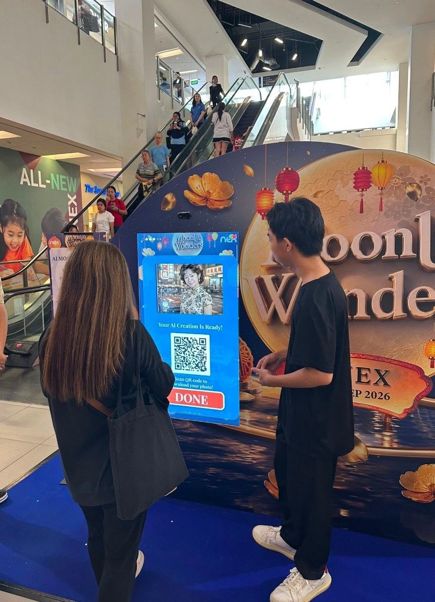 AI photobooth kiosk at a shopping-mall event, guest scanning the QR code to download the portrait